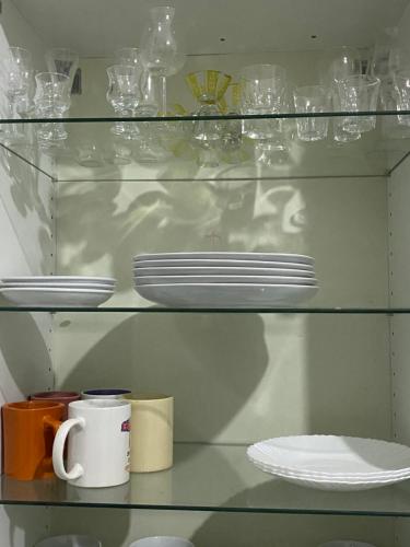 姆布尔Residences Fama的玻璃架上装有盘子和杯子,盘子