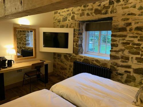 巴拉撒拉Trail Lodge的一间卧室设有石墙、一张床和一张书桌