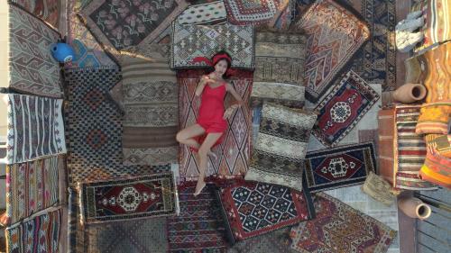 格雷梅Goreme Palace Cave Suites的一张坐在地毯上的红色连衣裙中的女人的画