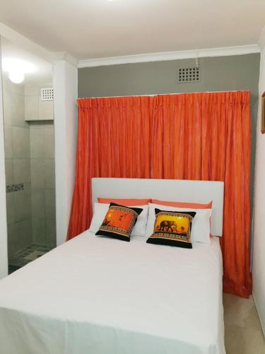 开普敦Lyronne Guest house, Shuttle and Tours的卧室配有白色的床和橙色窗帘