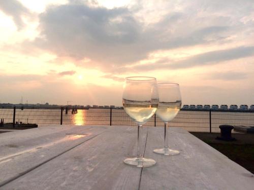 奥尔本尼兹Marina Lodge的两杯酒杯坐在水边的桌子上