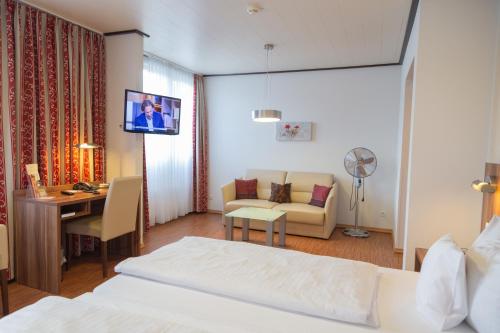 博帕德Das Ebertor - Hotel & Hostel的酒店客房设有一张床、一张书桌和一台电视机。