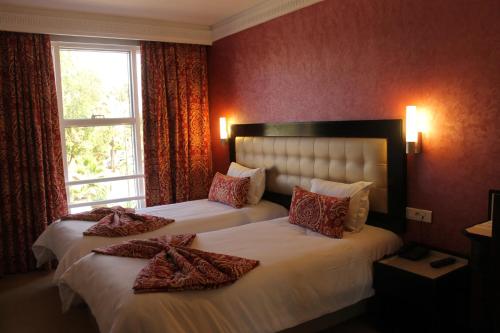 卡萨布兰卡阿尔瓦利德酒店的红色墙壁的酒店客房内的两张床