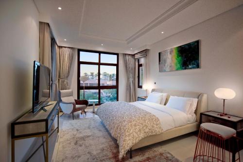 Rūl ḐadnāDibba, Villa 61 - Mina Al Fajer, Dibba Al Fujairah的一间卧室配有一张床、一台电视和一个窗口