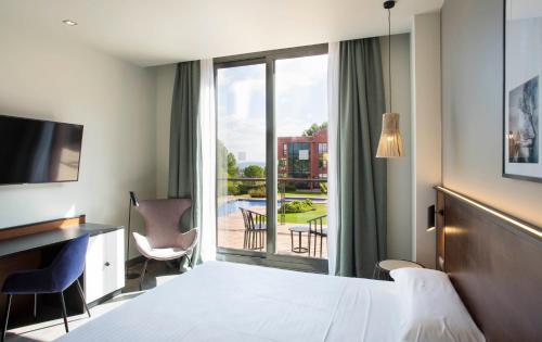 马尔托雷尔Hotel Barcelona Golf Resort 4 Sup的配有一张床、一张书桌和一扇窗户的酒店客房