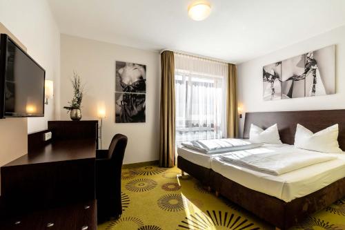 因戈尔施塔特伽勒瑞阿尔特斯塔德酒店的一间卧室配有一张床、一张书桌和一台电视