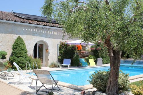 FronsacLes charmes de Vincent - le loft Cabernet的一座带椅子的游泳池,一座房子旁的树