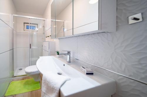 洛帕Apartments Arbis的白色的浴室设有水槽和卫生间。