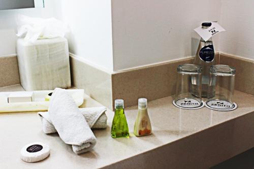 提瓦坎Hotel Zenith的浴室柜台配有带毛巾和瓶子的盥洗盆
