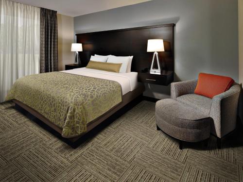 WarrendaleStaybridge Suites - Pittsburgh-Cranberry Township, an IHG Hotel的配有一张床和一把椅子的酒店客房
