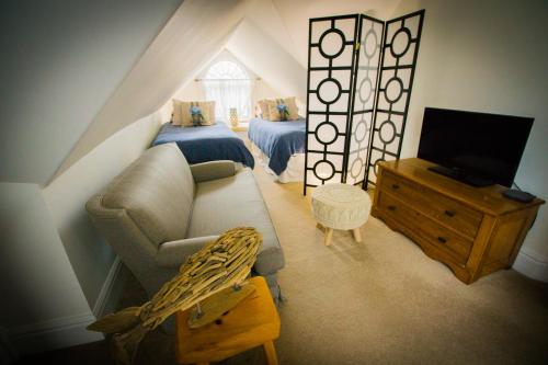 斯特拉福德Tranquil Days Guest House的阁楼间配有沙发、床和电视。