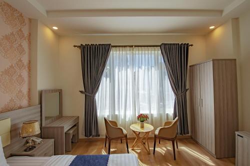 大叻Khanh Uyen 1 Hotel的一间卧室配有一张床、一张桌子和一个窗户。