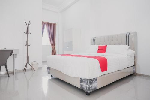 占碑市RedDoorz Syariah near Arafah Hospital Jambi的白色卧室配有一张带红色枕头的大床
