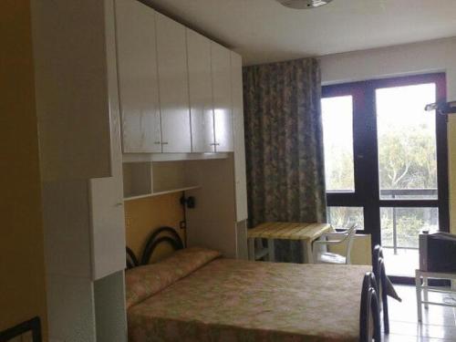 坎波马里诺内图诺公寓式酒店的一间卧室设有一张床、一个窗口和一张桌子