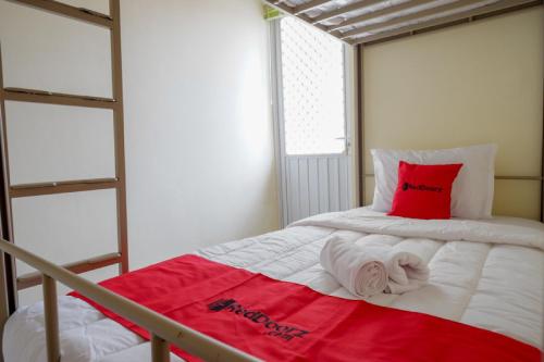 三宝垄RedDoorz Hostel near Kota Lama Semarang的一间小卧室,配有一张带红色枕头的床