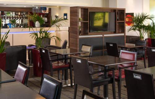 达特福德快捷假日达特福德桥酒店的餐厅设有桌椅和平面电视。