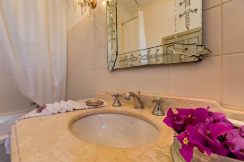 切什梅艾佩尤尔旅馆的浴室设有水槽、镜子和紫色的鲜花