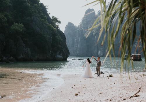 吉婆岛ĐẠI THỦY Hotel的站在海滩上的新娘和新郎