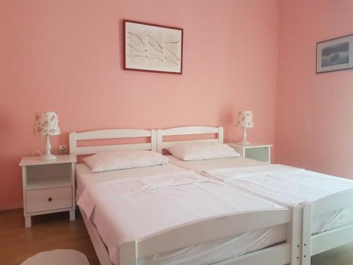 卡尔卢巴格Hotel Palace Vrkljan的卧室内的两张床,配有粉红色的墙壁和两盏灯。