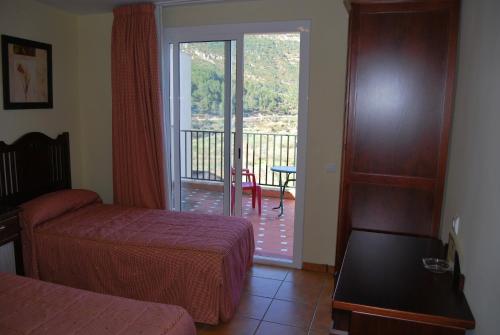 Cirat拉彼德拉德尔美迪蒂亚酒店的酒店客房设有一张床和一个带滑动玻璃门的阳台