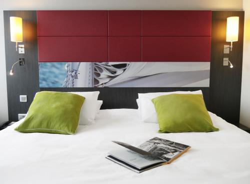 翁弗勒尔翁弗勒尔美居酒店的床上的书,带两个绿色枕头