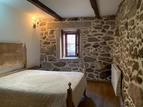 皮同伊斯-达斯-朱尼亚斯卡萨坎普费雷拉度假屋的一间卧室设有一张床和石墙