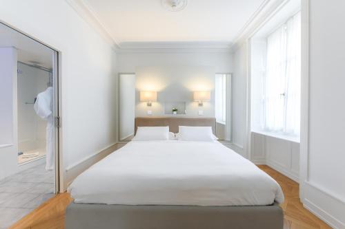 日内瓦瑞士豪华公寓酒店的白色客房内的一张大床,配有镜子