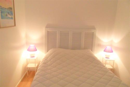 Guidel-PlageApt 6 pers - Magnifique vue mer - Belle terrasse - AZILIZ的卧室配有带两盏灯的白色床