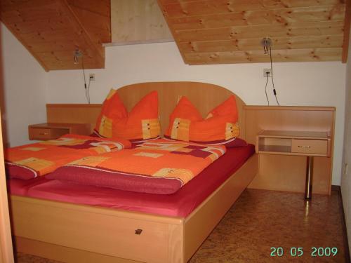 拉赫塔尔Ferienwohnung A 55 m2的一张带橙色棉被和枕头的床