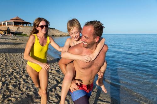 阿布达巴Three Corners Equinox Beach Resort的一名男子和两名妇女在海滩上玩耍