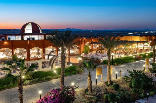 阿布达巴Three Corners Happy Life Beach Resort的享有棕榈树建筑的夜间景色