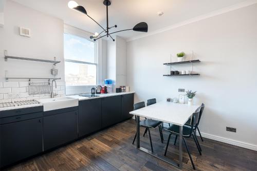 伦敦HSA - Shoreditch的厨房配有黑色橱柜和桌椅
