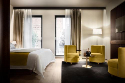 米兰Speronari Suites的一间卧室配有一张床和两张黄色椅子