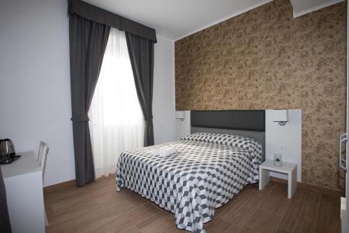 奇维塔韦基亚Guesthouse Porto di Roma的一间卧室配有一张带 ⁇ 子毯子的床和窗户