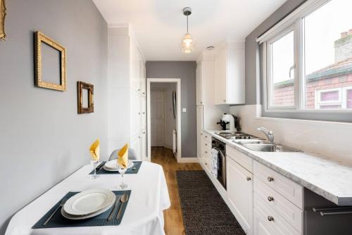 沃特福德The Bluebird - One Bedroom Apartment in Watford的厨房配有白色橱柜、水槽和窗户。