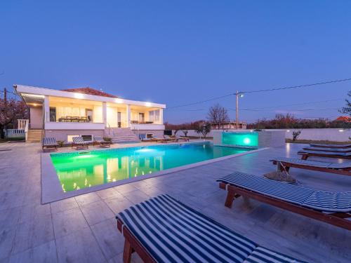 伽罗瓦克Classy Holiday Home in Galovac with Swimming Pool的一座晚上设有游泳池的房子
