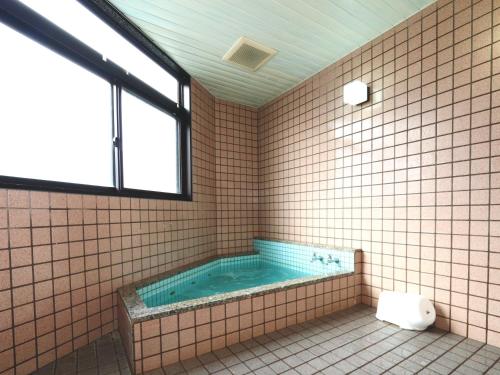 大町市纳库罗斯传统日式旅馆 的一间带卫生间和窗户的浴缸的浴室