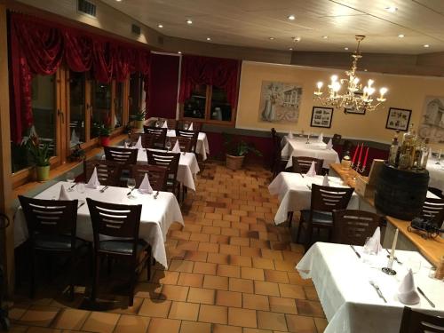 Wattwil莫特里那酒店的餐厅配有白色的桌椅和吊灯
