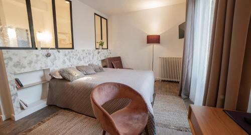 蒙蒂尼亚克Les chambres de l'ATELIER à Montignac Lascaux的一间卧室配有一张床、一张桌子和一把椅子