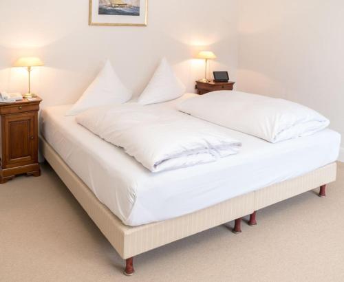 施特兰德Strandhotel Strande的一张配有白色床单和枕头的大床