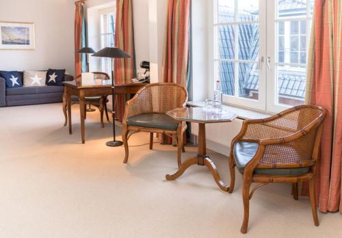 施特兰德Strandhotel Strande的客厅配有桌椅和窗户。