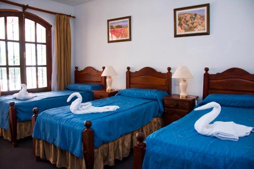 梅洛El Cortijo Apart - Hotel的一间设有三张床的房间,上面有天鹅
