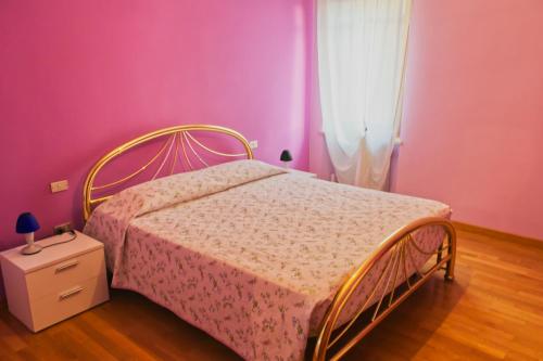 维罗纳B&B Casa a colori的一间卧室配有一张粉红色墙壁的床