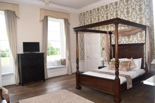 布雷伍德The Clock House的一间卧室配有一张天蓬床和一台电视机