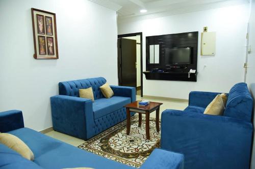 奈季兰شقق جنان المفروشة Jenaan Apartments的客厅配有2把蓝色椅子和电视