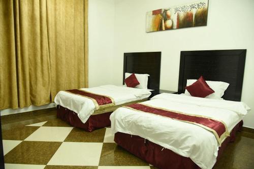 奈季兰شقق جنان المفروشة Jenaan Apartments的一张位于带 ⁇ 形地板的客房内的两张床