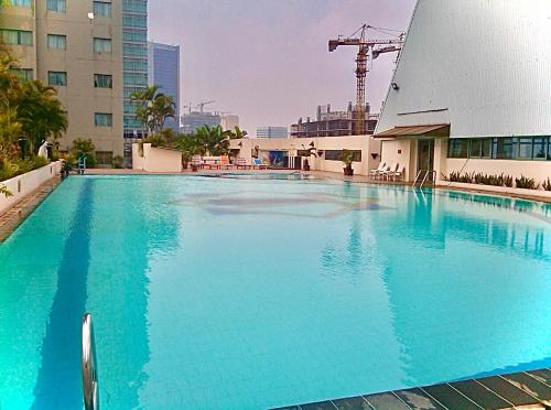 雅加达Ambassador Apartment Kuningan的大楼前的大型蓝色游泳池