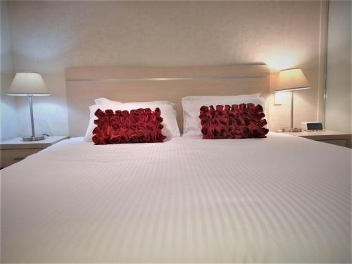 阿德莱德Hi 5 star luxury Adelaide City Apartment的一张带两个红色枕头的白色床