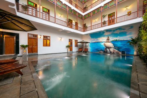 蓬蒂切里Grand Hotel D'Europe的一座带壁画的建筑中的大型游泳池