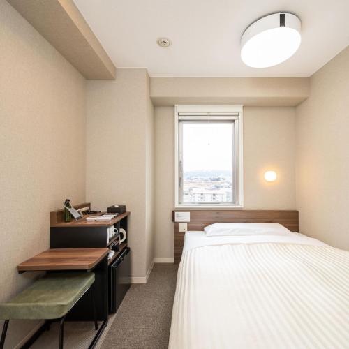 上越市Super Hotel Joetsu Myoko-Eki Nishiguchi的客房设有床、书桌和窗户。